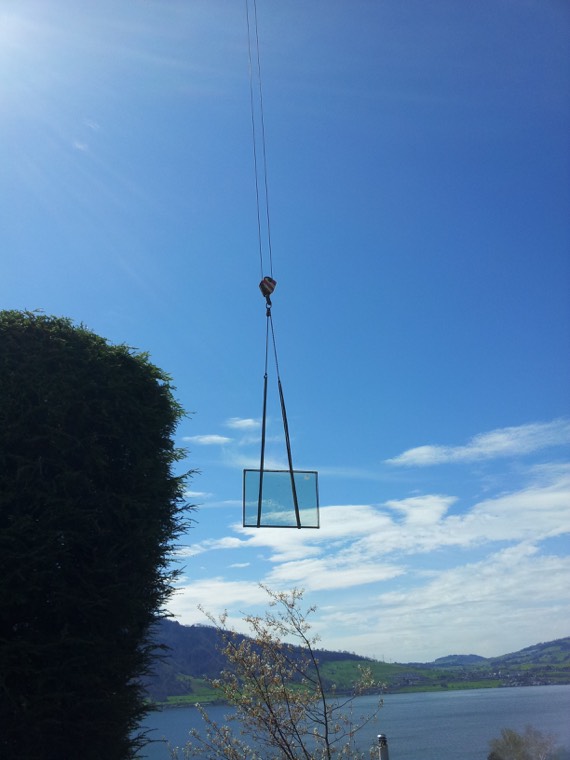 Glaselement hängt am Kran vor blauem Himmel